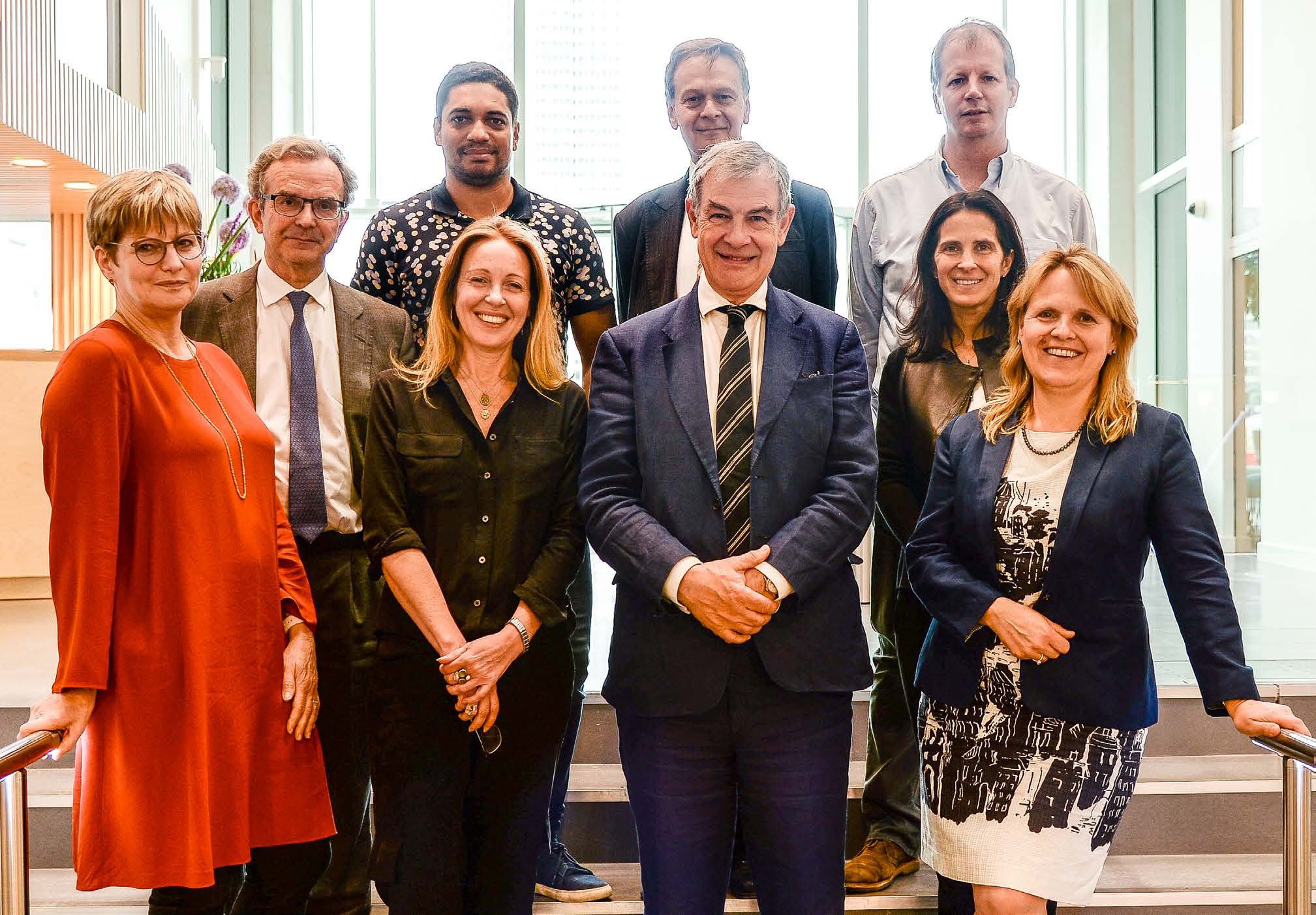 Group photo of ten diverse professionals, standing together and smiling at the camera, likely a team or board.