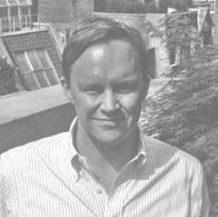 Headshot of a man with short hair wearing a striped collared shirt.