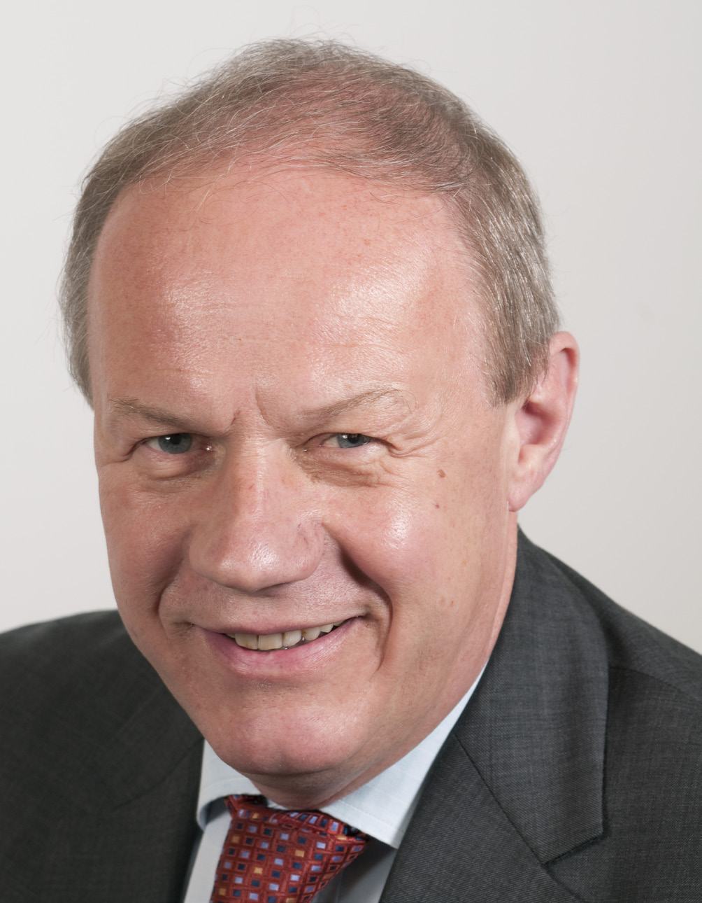 Headshot of a smiling man with light brown hair and a suit.