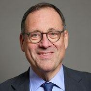 Headshot of an older man wearing glasses and a suit, smiling.