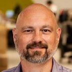 Headshot of a bald man with a beard, smiling slightly.