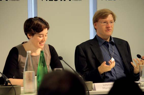 A woman and a man, identified as Louise Marsh, participating in a panel discussion with microphones and water bottles on the table.