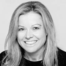 Black and white headshot of a smiling woman with blonde hair.