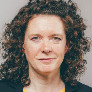Headshot of a woman with curly brown hair, looking at the camera with a neutral expression.