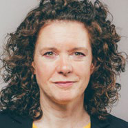 Headshot of a smiling woman with curly brown hair.