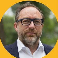 Headshot of a man with glasses and a beard, looking at the camera, framed by a yellow circle.