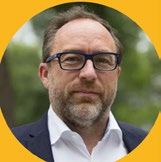Headshot of a man with a beard and glasses in a yellow circular frame.