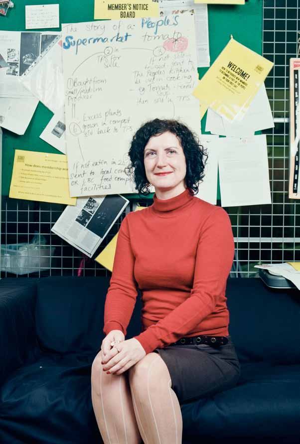 Woman in a red turtleneck sits on a couch, with a "Member's Notice Board" detailing supermarket info behind her.