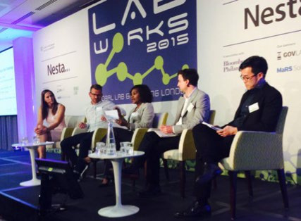 Panel discussion at the Lab Works 2015 event, featuring five speakers on stage with event branding in the background.