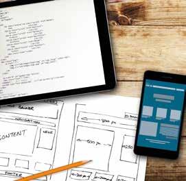 A tablet displaying code, a smartphone showing a user interface, and hand-drawn website wireframes on paper, illustrating the design process.