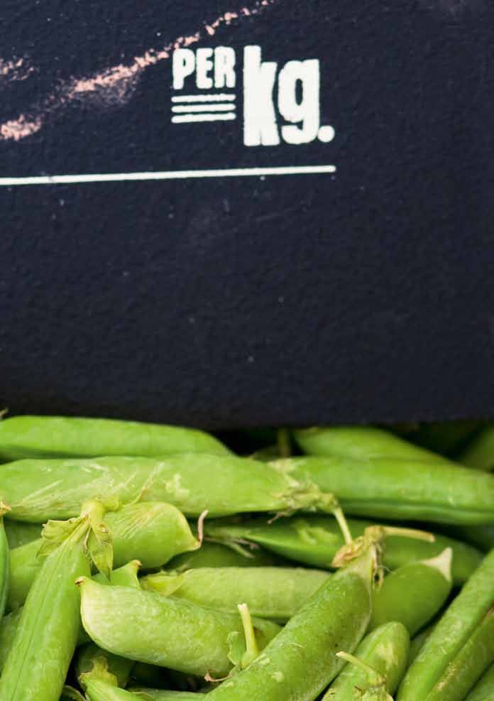 Fresh green peas with a chalkboard sign displaying "PER Kg." as a unit of measurement.