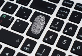 Close-up of a keyboard with a fingerprint icon on a key, symbolizing biometric security or digital identity.