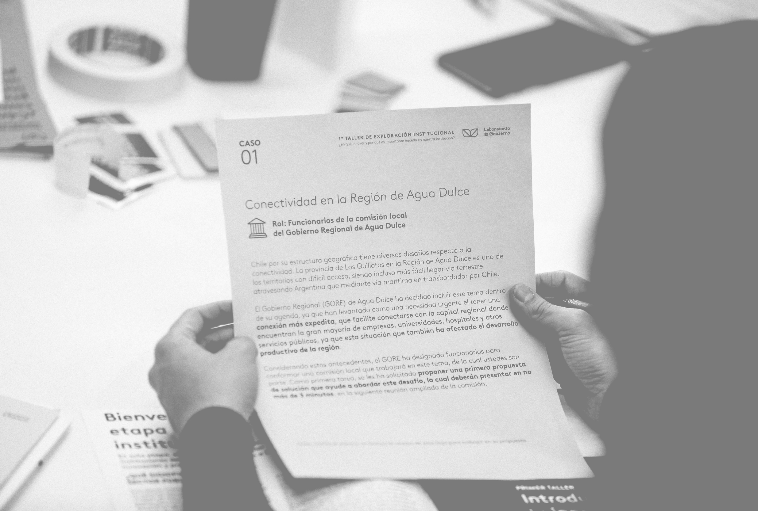 Hands hold a document titled "Conectividad en la Región de Agua Dulce," likely a case study or report, providing contextual information.