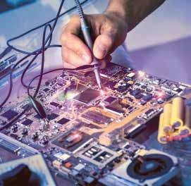 A hand using a tool to work on a complex circuit board with various electronic components.