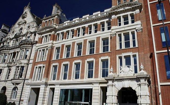 Exterior view of a large, ornate brick building with many windows, alongside a modern building.