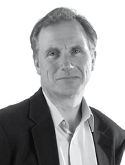Black and white headshot of a man with short hair, wearing a collared shirt and jacket, looking forward.