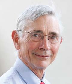 Headshot of an older man with gray hair and glasses, smiling slightly.