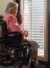 Elderly woman in a wheelchair looking out a window.