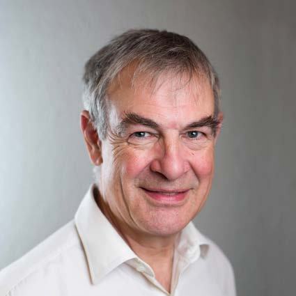 Headshot of a smiling older man with gray hair, wearing a white collared shirt.