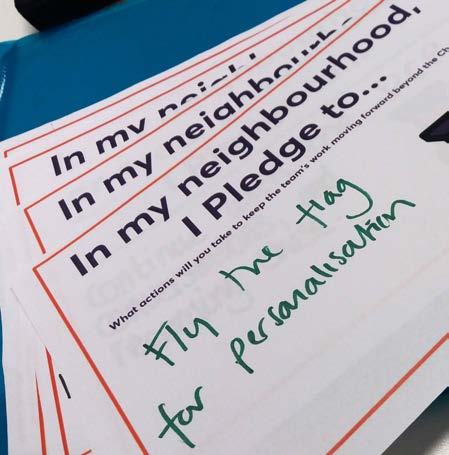 Stacked papers showing workshop prompts about pledges and actions, with handwritten text "Fly the flag for personalisation".