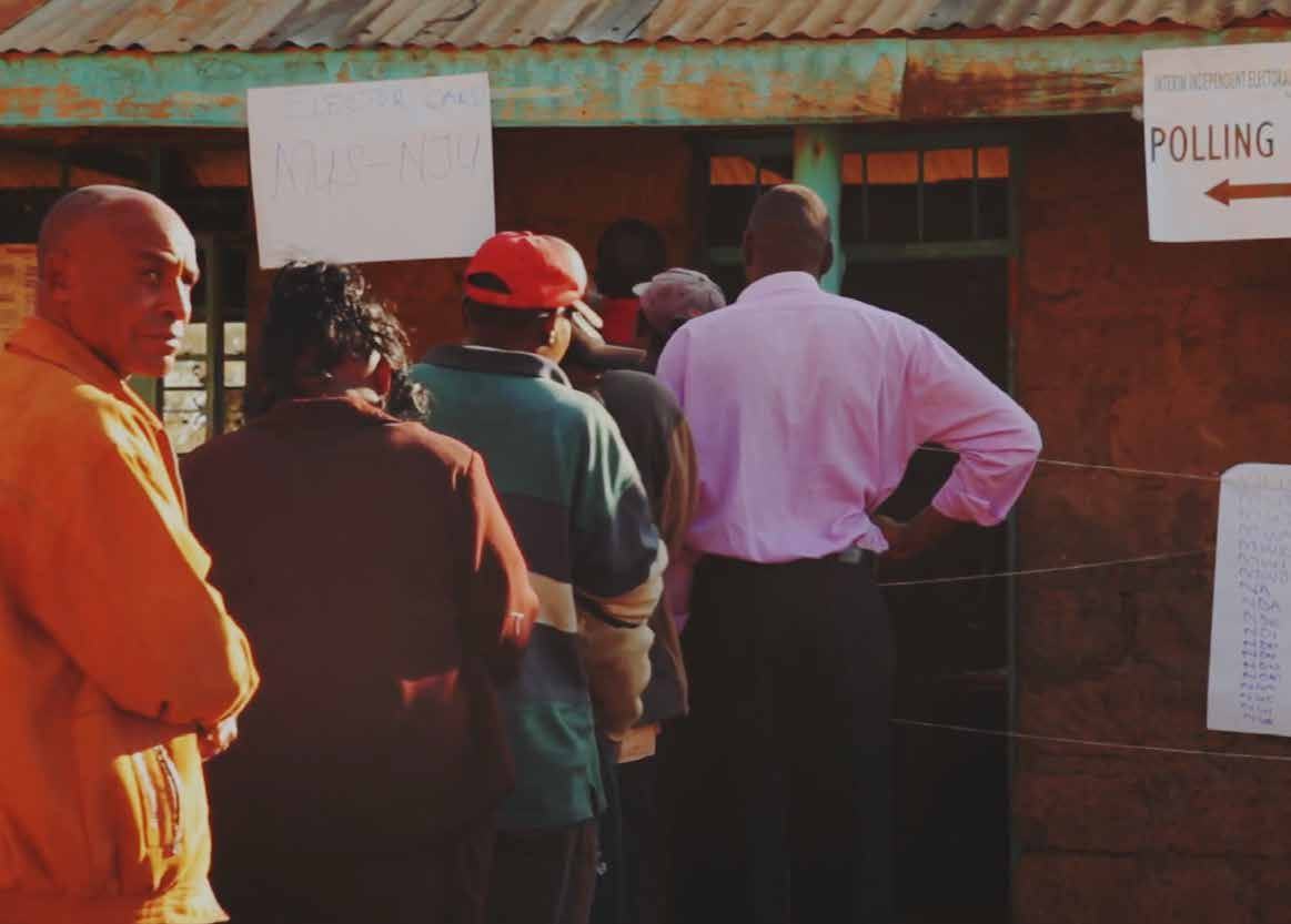 People queueing outside a building with "POLLING" and "ELECTOR CARD" signs, indicating an election or voting event.