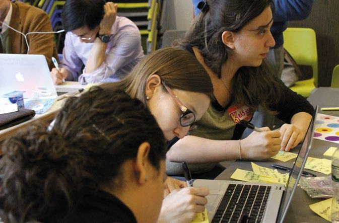 People working collaboratively at laptops and writing on sticky notes during a meeting or study session.