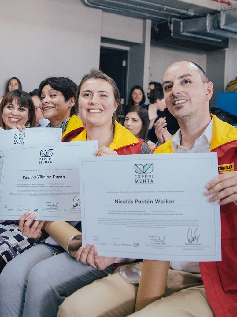 Two smiling individuals hold up certificates from "EXPERIMENTA," signifying their completion or achievement in a program.