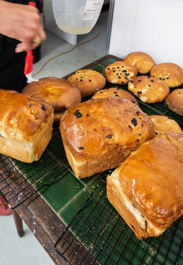 Rows of freshly baked, glossy loaves of bread and round buns on cooling racks.