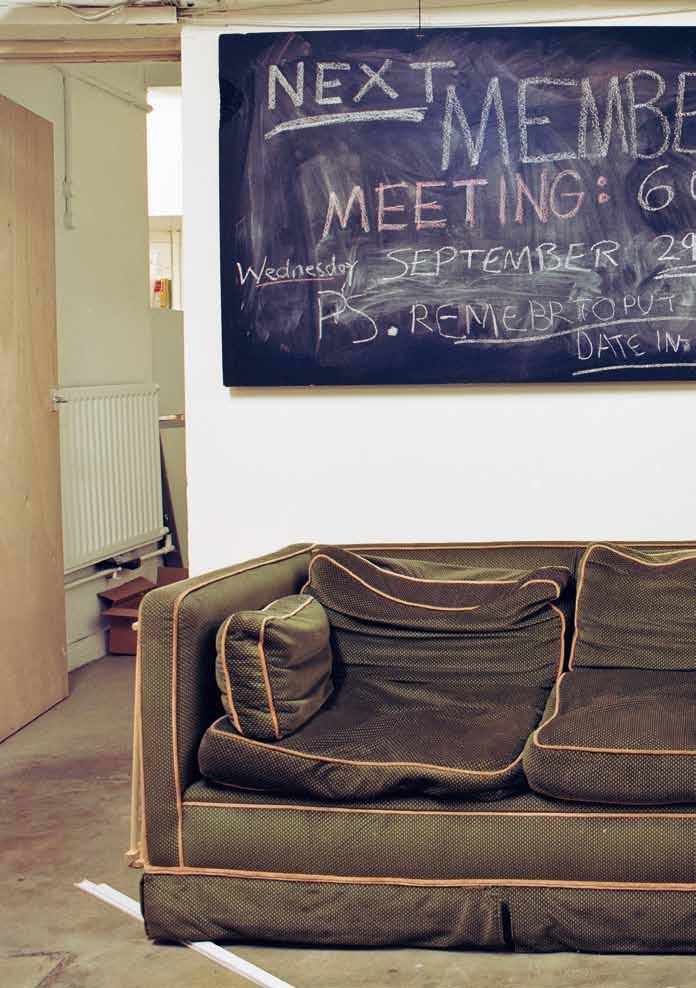 A dark green couch in a room with a chalkboard sign announcing "NEXT MEMBERS MEETING: 6:00pm Wednesday SEPTEMBER 29th" and a reminder.