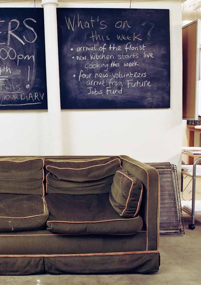 A dark green couch with a chalkboard sign listing "What's on this week?" including "arrival of the florist" and new volunteers.