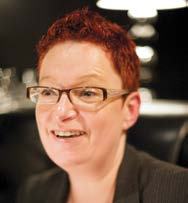 Headshot of a smiling woman with short red hair and glasses.
