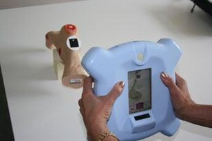 Hands holding a blue tablet-like device displaying an internal view, possibly interacting with an anatomical model.