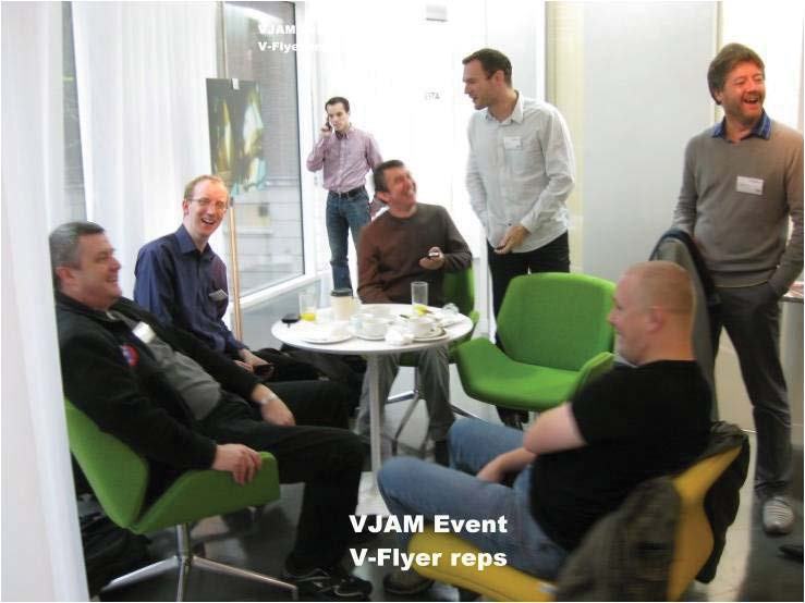 Men gathered at a VJAM Event, identified as V-Flyer representatives, socializing around a coffee table.