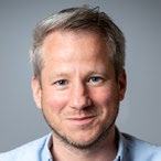 Headshot of a smiling man with short grey hair and a beard, possibly a staff member or featured individual.