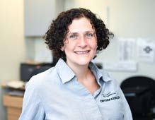 Headshot of a smiling woman with curly brown hair, glasses, and a light blue polo shirt with the "OrthoSkills" logo.