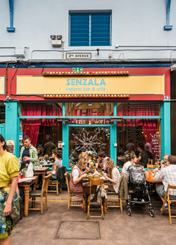 Exterior of Senzala Creperie Bar & Cafe with outdoor seating, people dining and a blue upper facade.