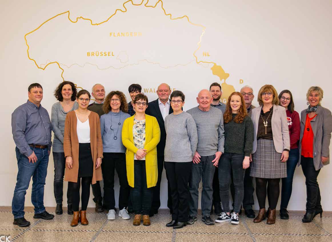 Group photo of approximately 18 people standing in front of a wall with a map outline of Belgium, labeled with regions like Flanders and Brussels.