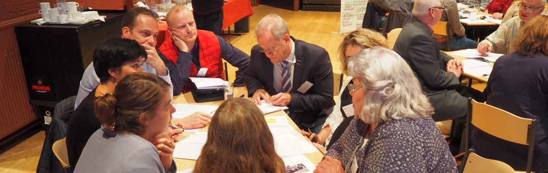 Group of diverse people seated around a table, actively participating in a discussion or meeting.
