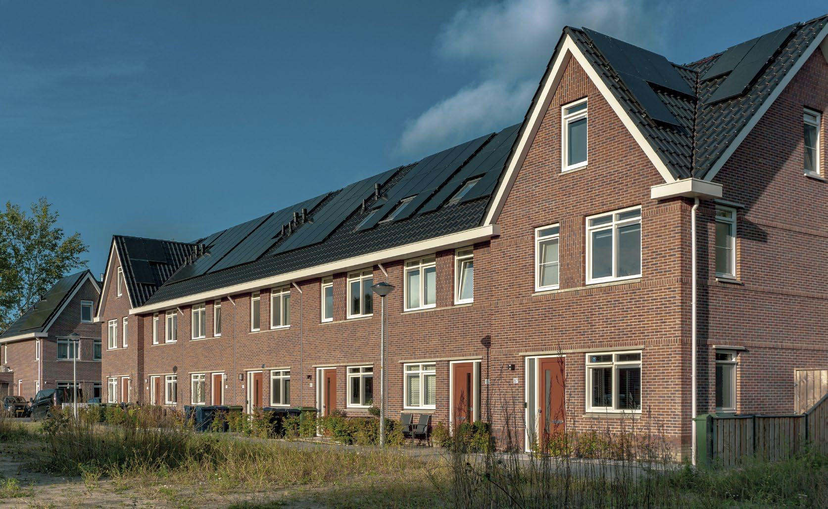 Row of modern brick houses with solar panels on their roofs, illustrating renewable energy in residential architecture.