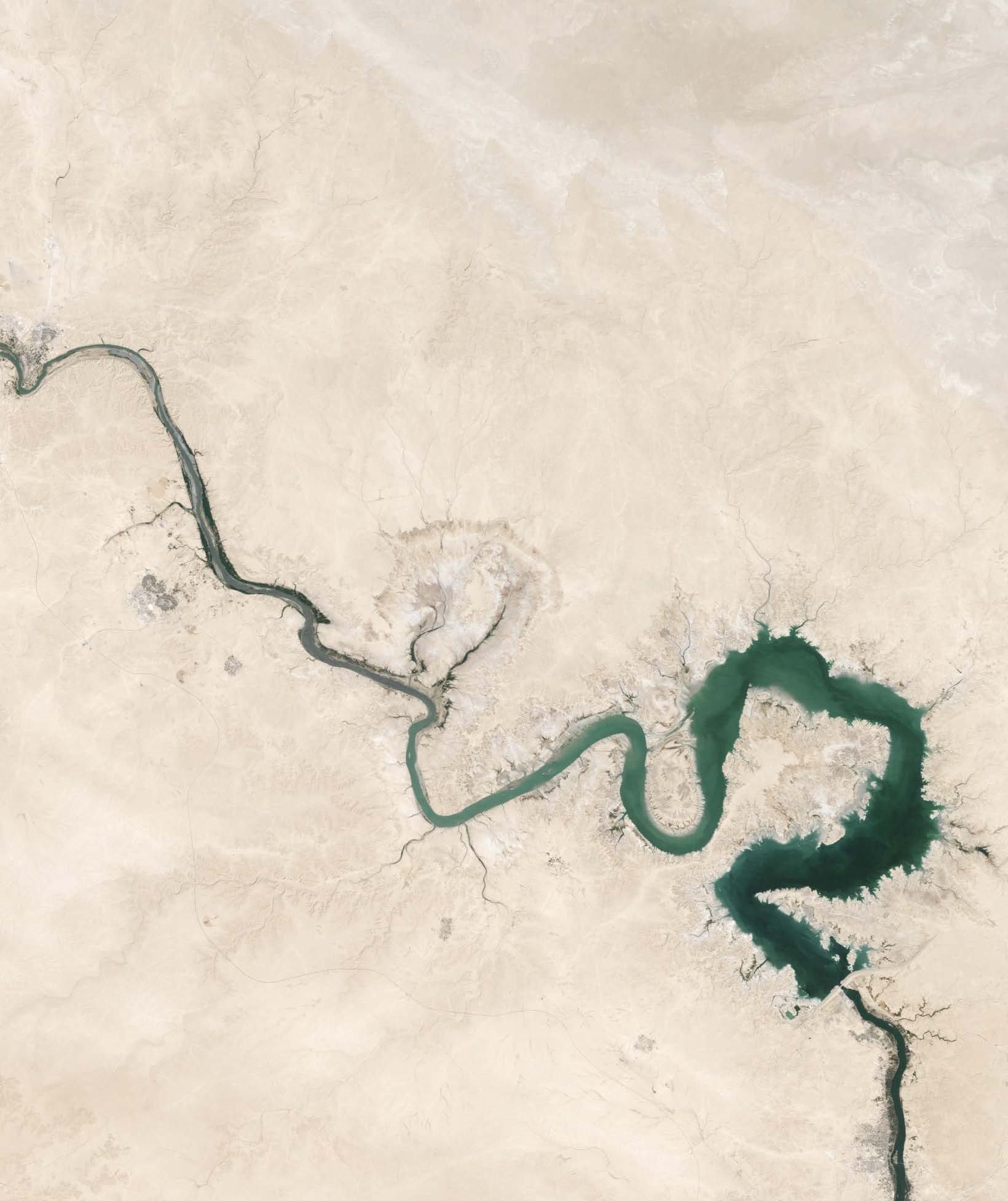 Aerial view of a winding river and a large, irregularly shaped lake in a dry, desert landscape.