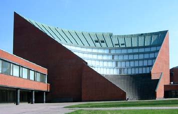 Exterior view of a modern building with a curved, multi-tiered green roof and red brick walls.