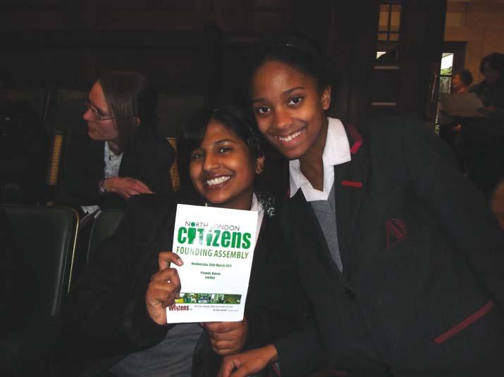 Two young women holding a booklet for the "North London Citizens Founding Assembly".