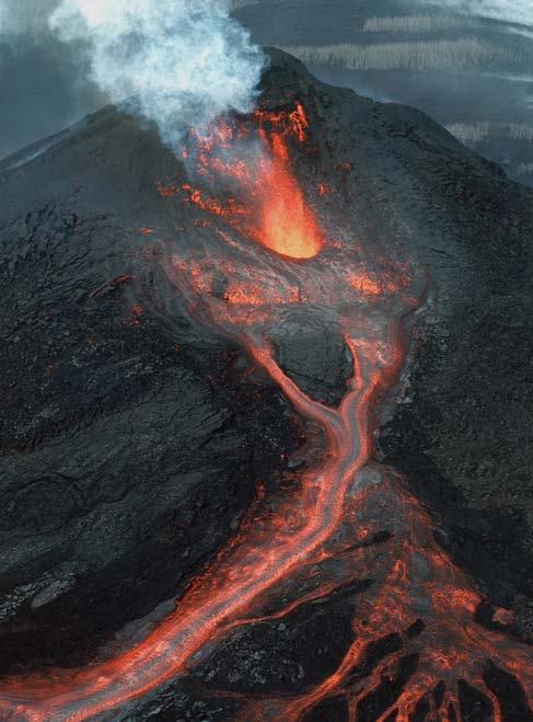 Aerial view of an active volcano with bright orange lava flowing down its dark slopes and smoke rising from the crater, showing an eruption.