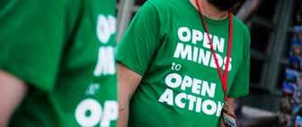 Two people wearing green t-shirts with the message "OPEN MINDS to OPEN ACTION" printed in white on the front.