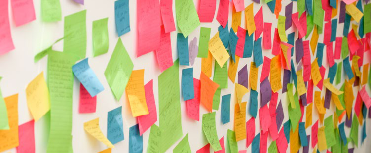 A wall covered in numerous colorful sticky notes, representing brainstorming ideas or project progress.
