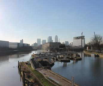 City skyline seen across a river with industrial docks and buildings in the foreground.