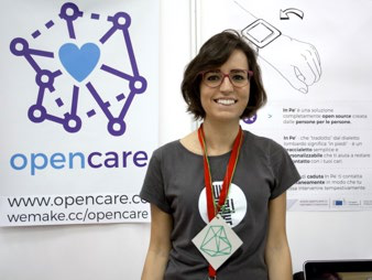 Woman standing by a banner for "opencare" showing a network diagram, heart symbol, and smart wristband illustration with text.