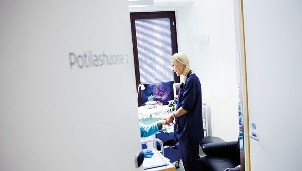 A healthcare professional attending to a patient in a bright patient room labeled "Potilashuone 2".