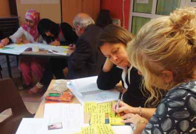 Group of people at a table, engaged in a collaborative workshop, writing on papers and sticky notes.