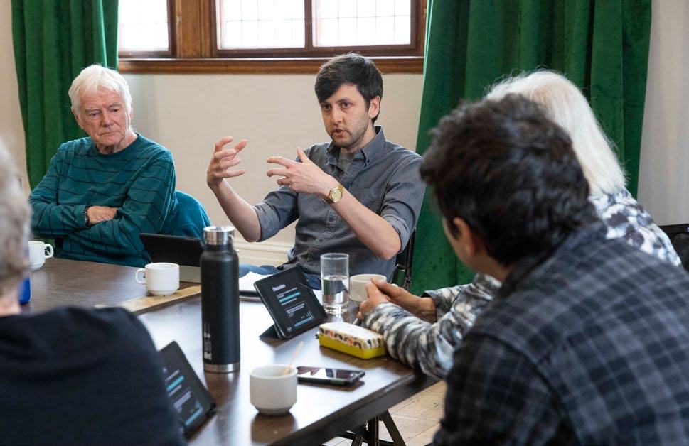 Group of people sitting around a table with tablets, engaged in a discussion, illustrating the process in action.